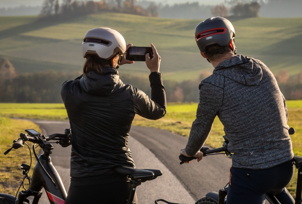 Mann und Frau stehen mit Rad und Frau macht mit dem Handy ein Foto von der Landschaft